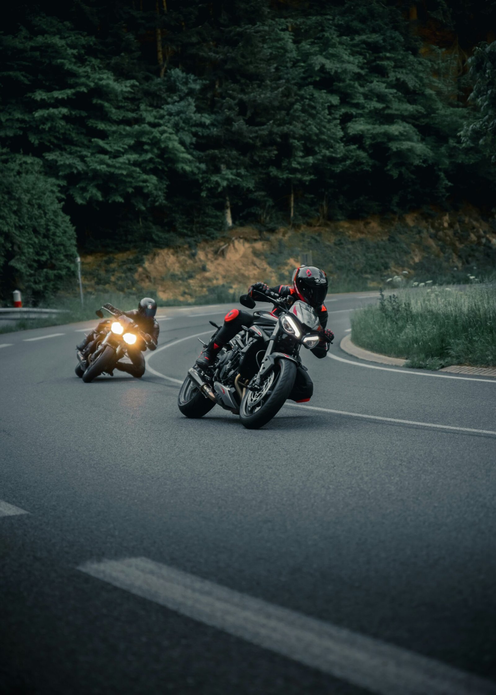 a couple of people riding motorcycles down a curvy road