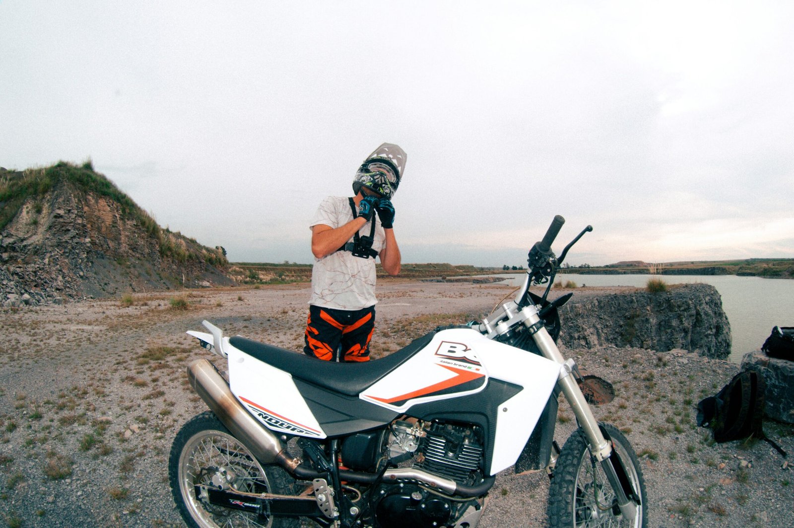 a man standing next to a motorcycle on a dirt road